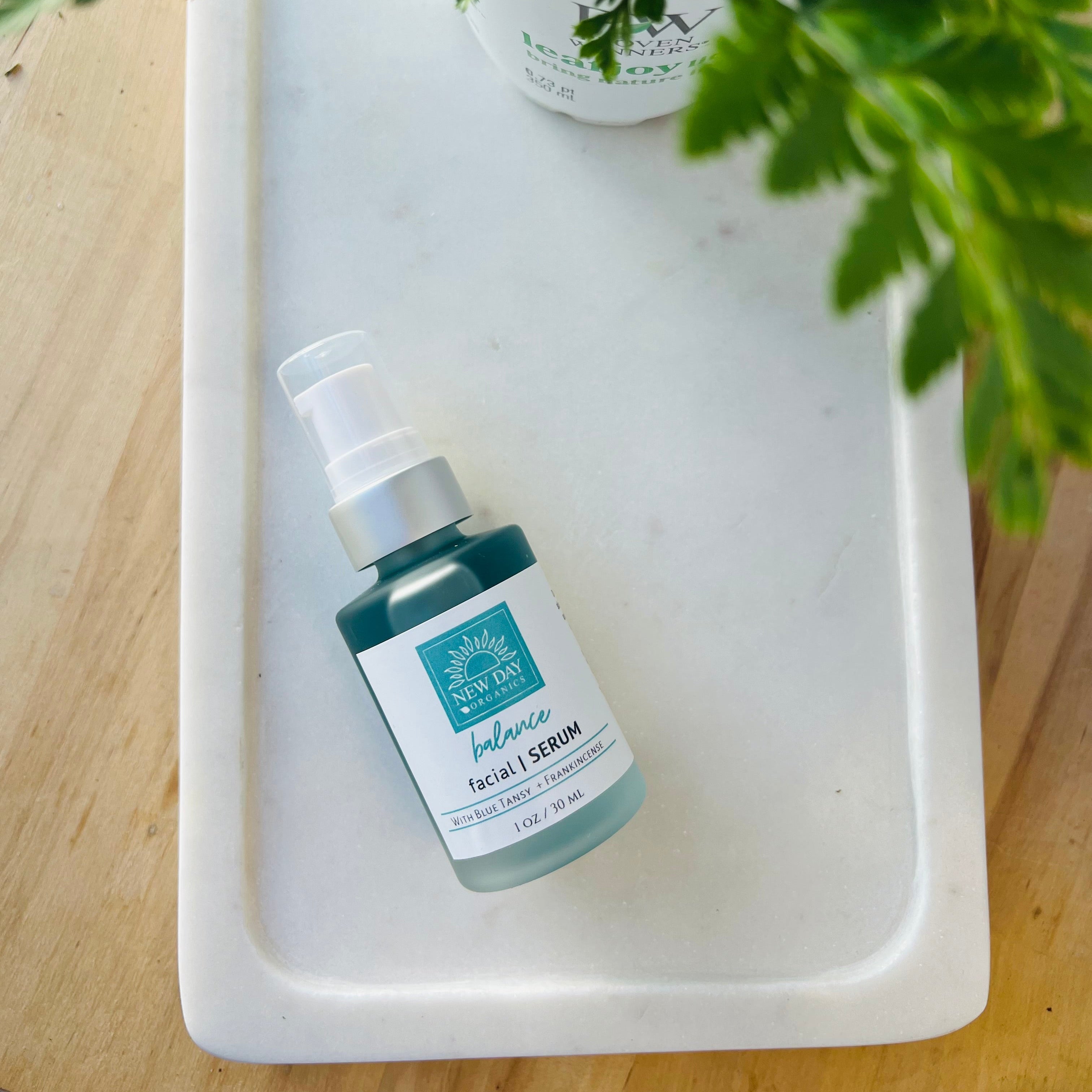 Skincare bottle on a white tray with a plant in the background