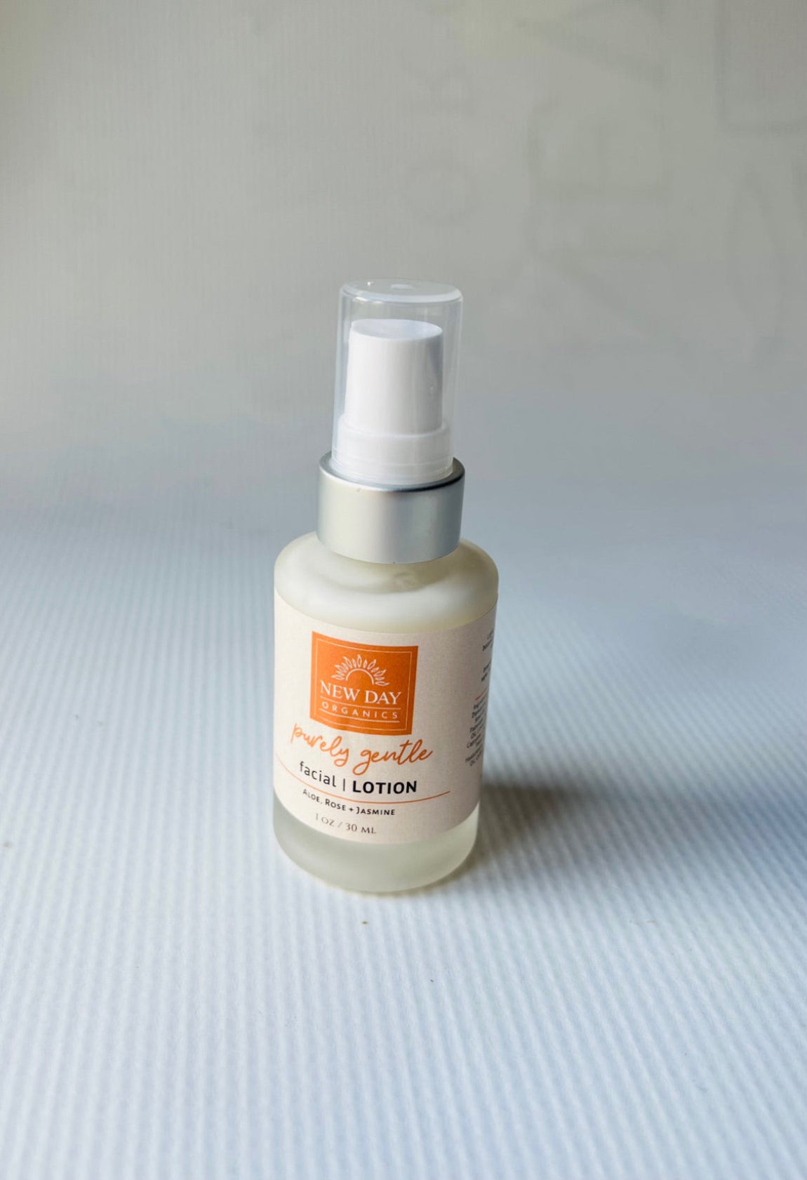 Bottle of facial lotion on a textured surface with a neutral background