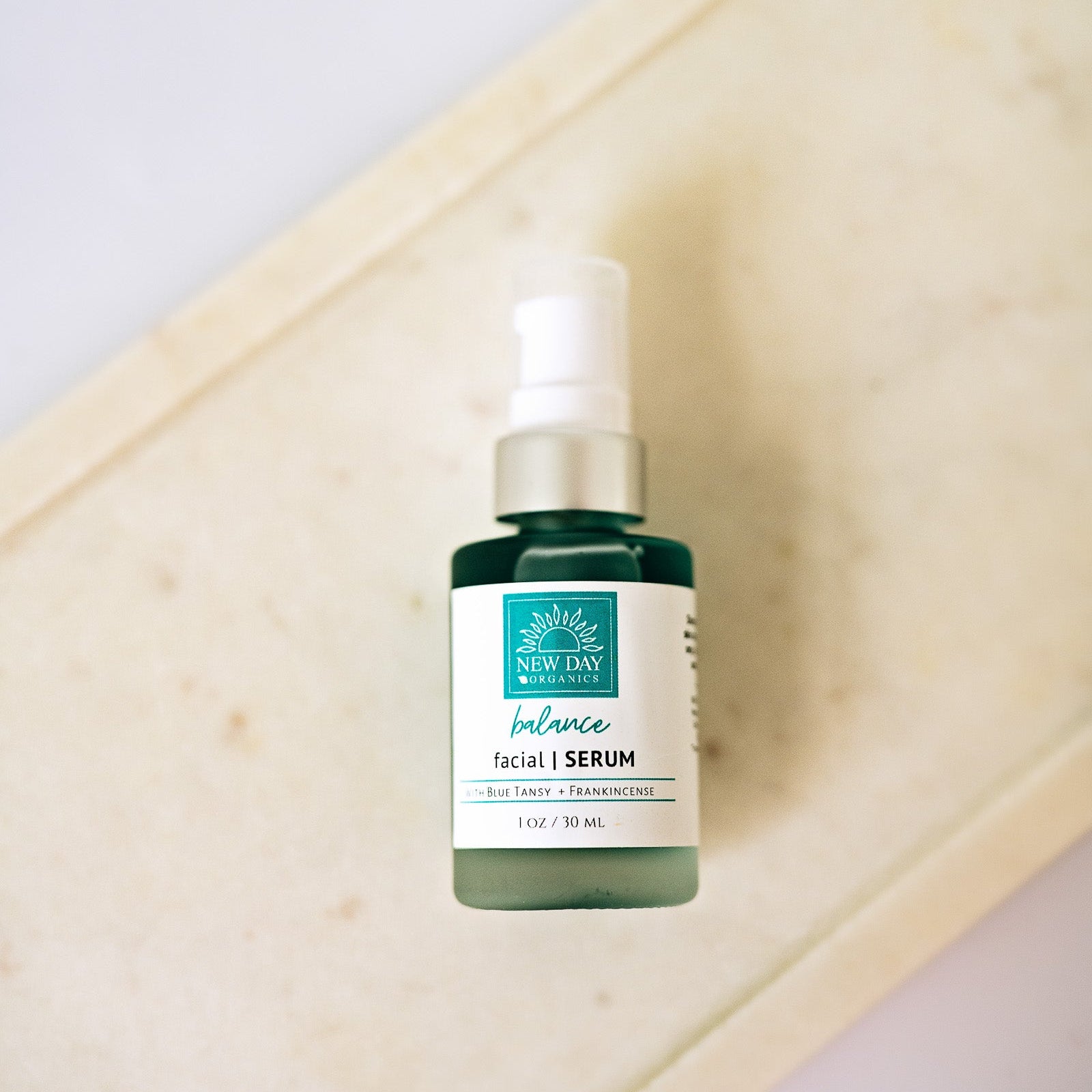 Skincare serum bottle on a wooden tray with a white background