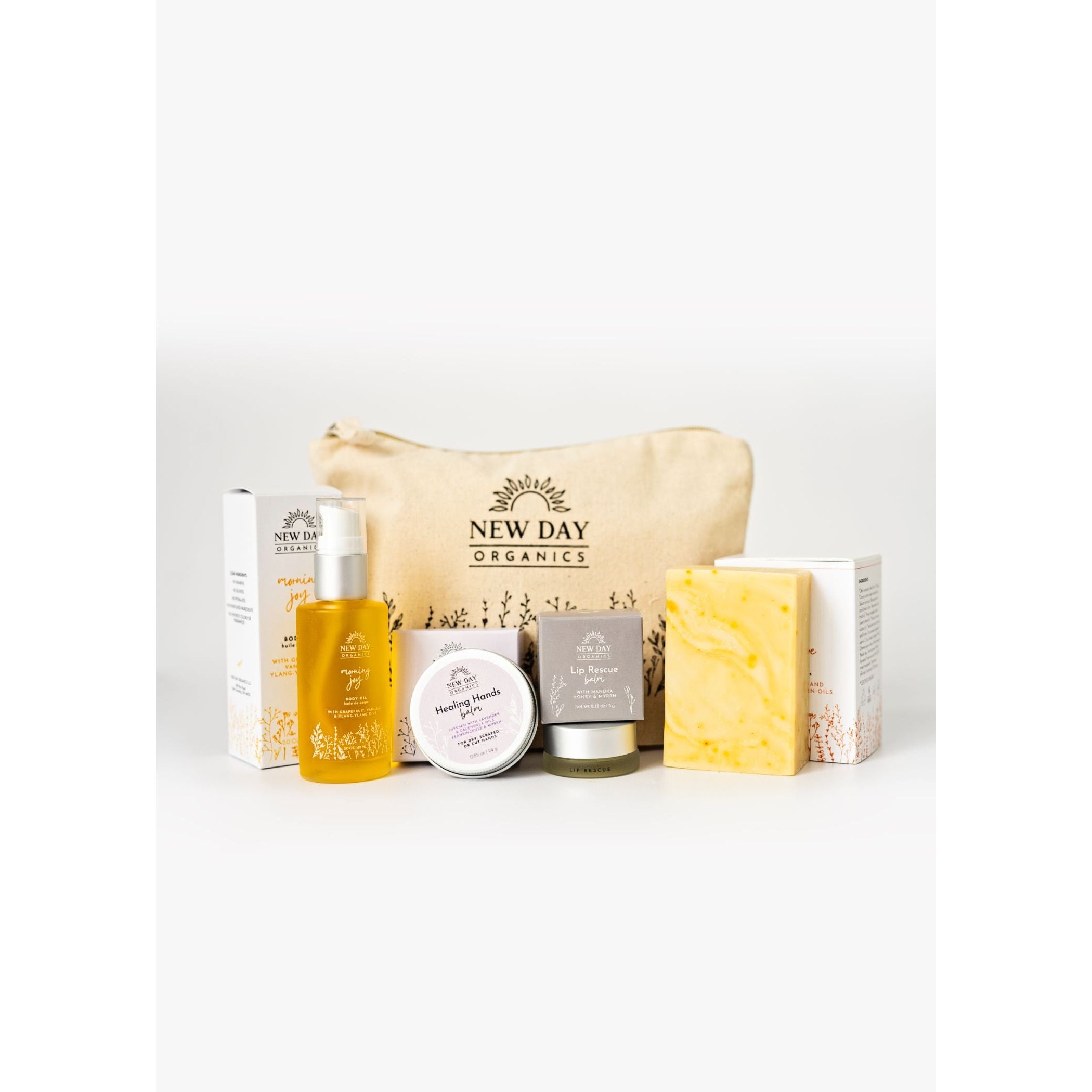 Collection of New Day Organics skincare products including a pouch, bottle, and bars on a white background.