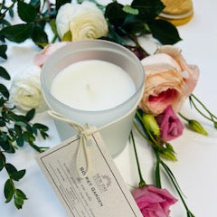 Candle in a silver holder with flowers and a tag on a white surface