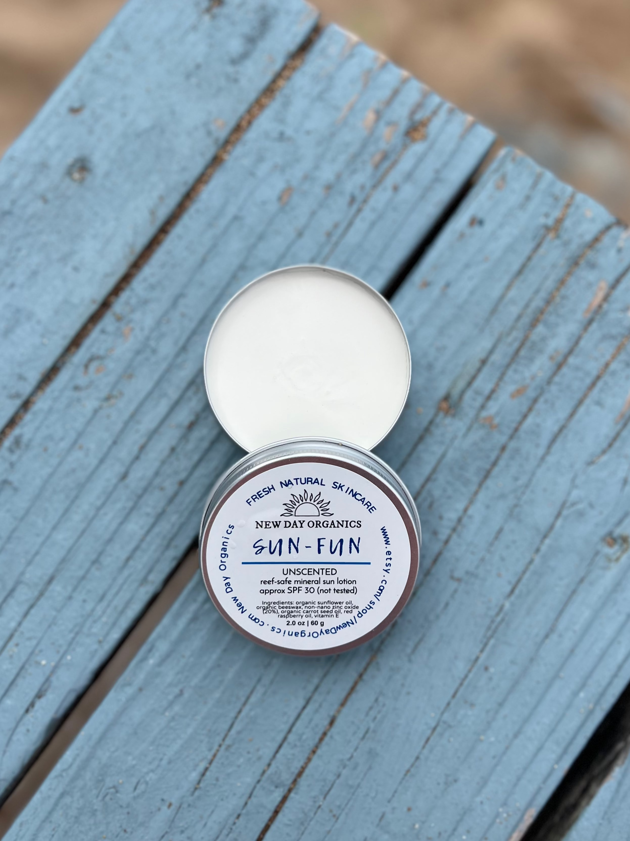 Tin of sunscreen on a blue wooden beach deck