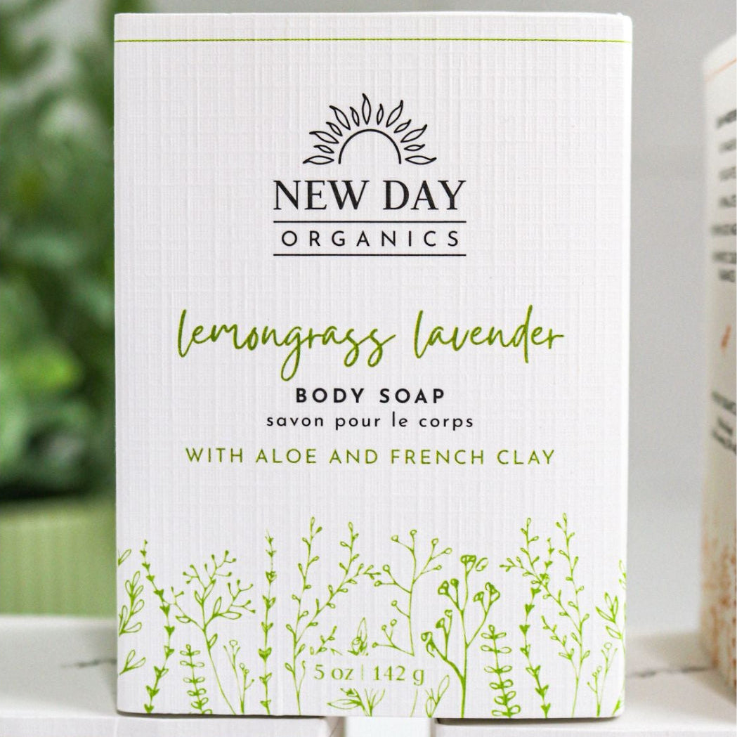 New Day Organics lemongrass lavender body soap packaging on a white surface with a blurred green plant in the background.