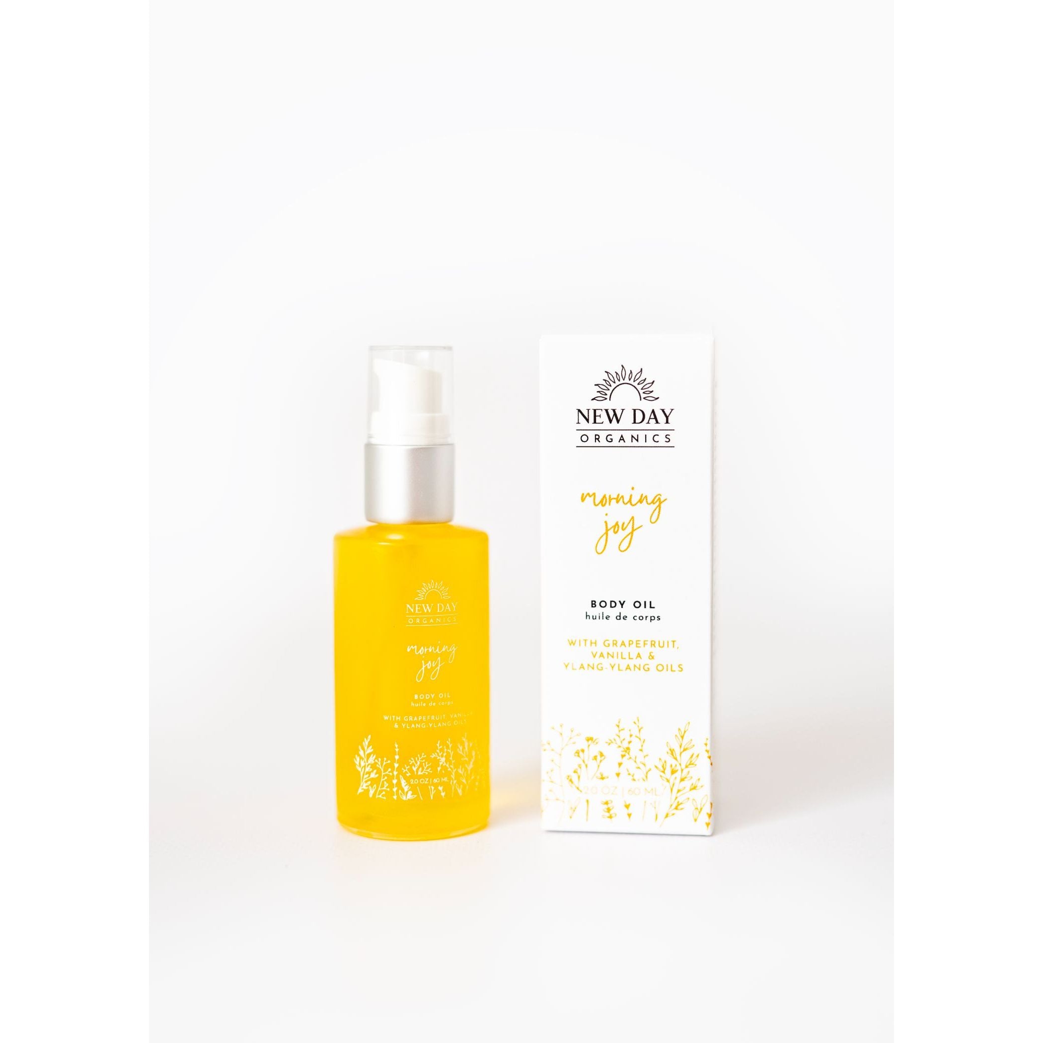 Yellow bottle and white box of New Day Organics body oil on a white background
