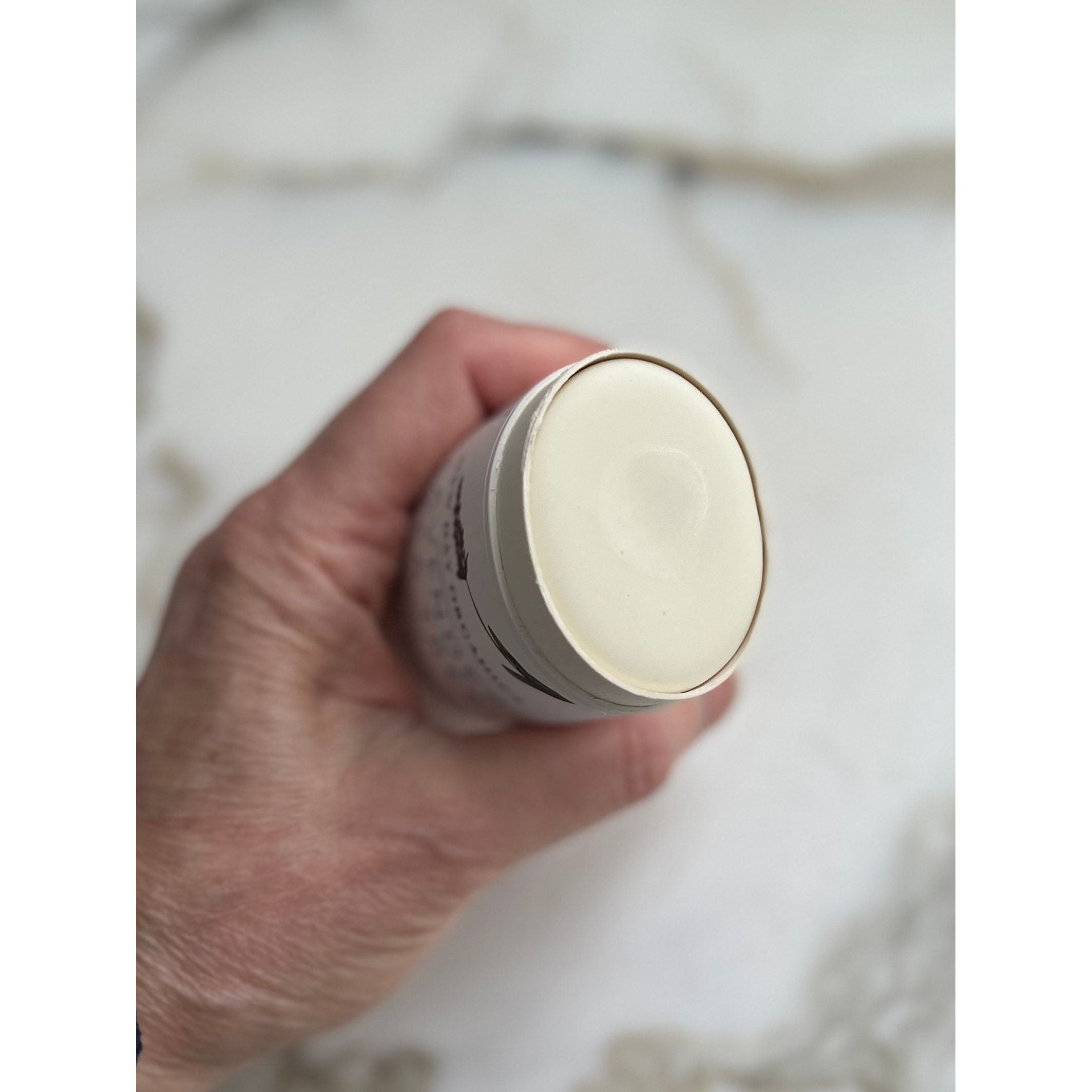 Hand holding a cylindrical light bulb against a neutral background