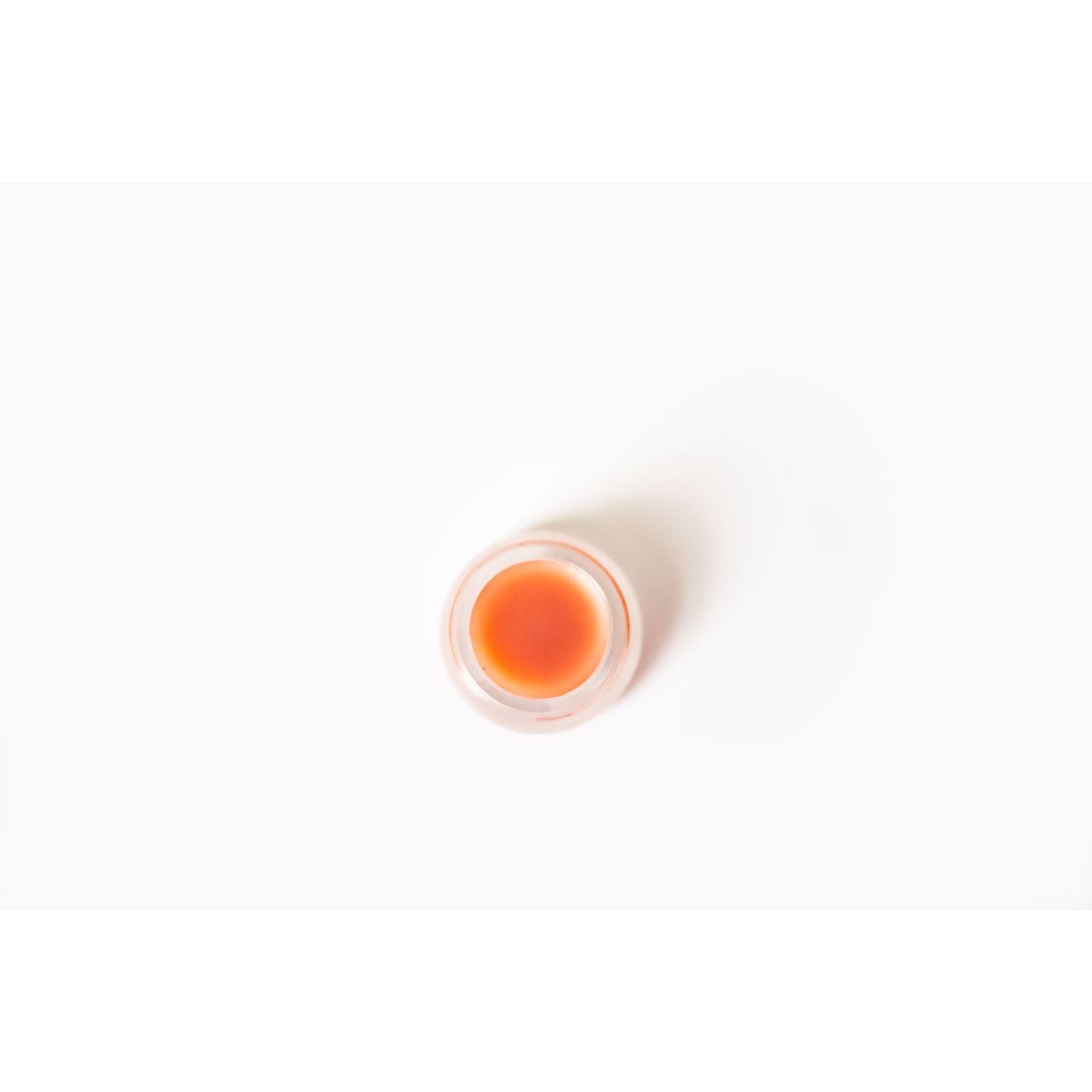 Small container of orange cream on a white background